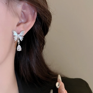 Detail of butterfly earring with mother of pearl and teardrop zircon on a model