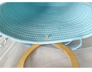 Detail of blue woven cotton tote bag with a round wooden handle and tulle ribbon decoration