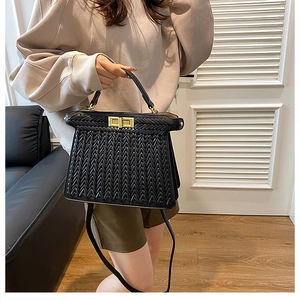Close-up of black woven handbag featuring elegant gold metal clasp and textured finish