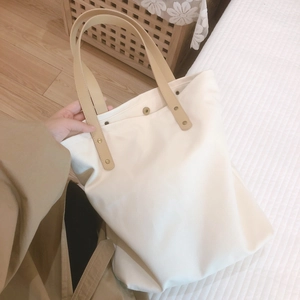 Minimalist cream canvas tote bag with faux leather handles and rivet details