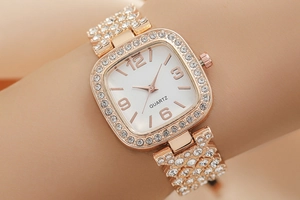 Close-up of rose gold square watch with sparkling rhinestones on model's wrist