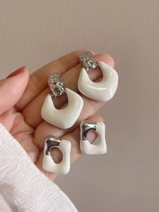Detailed view of white enamel geometric earrings with silver hammered metal texture