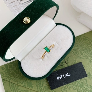 Twisted gold ring with rectangular green gemstone in a velvet box 45-degree angle view