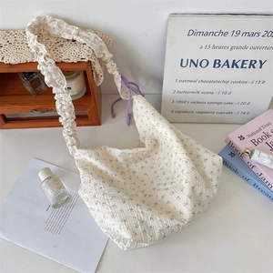 Détail du sac sous le bras à fleurs en crépon beige avec bandoulière à volants plissée