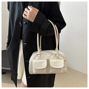 Model wearing a cream-colored minimalist square bag with dual front flap pockets