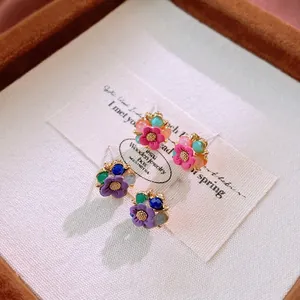 Elegant floral crystal stud earrings in pink and purple tones with golden centers