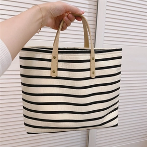 Detail of striped canvas tote with durable leather handles and metal rivet reinforcement