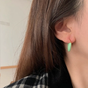 Close-up of a model wearing mint green enamel hoop earrings with gold plating