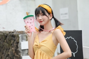 Pink watermelon shaped straw cup with matching shoulder strap held by a model