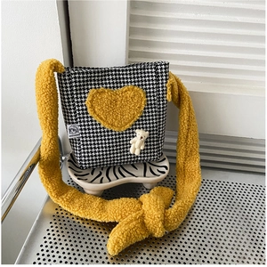 Détail du tissu pied-de-poule noir et blanc avec cœur en peluche jaune et ourson