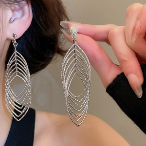 Macro detail of silver leaf-shaped hollow clip-on earrings with shimmering zircon texture