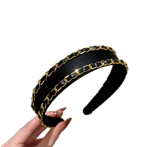 Elegant black fabric headband featuring woven gold metal chain and leather strap design