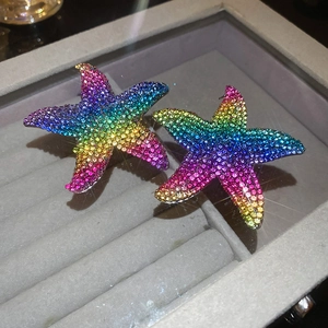 Macro detail of rainbow crystal starfish earrings on a premium velvet jewelry tray