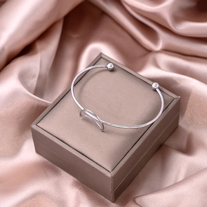 Detail of silver crescent moon open bangle bracelet displayed on a luxury jewelry box