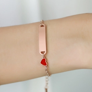Détail du bracelet en acier inoxydable rose doré avec plaque à graver et pendentif cœur