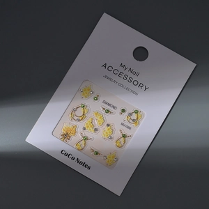 Detailed view of floral nail jewels with yellow blossoms and green gems on white card