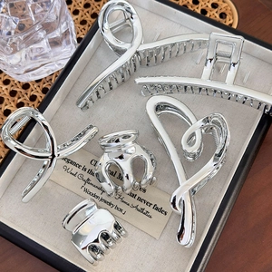 Five-piece silver metal hair claw set with heart and geometric designs in jewelry box