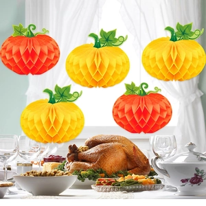 Set of orange and yellow 3D honeycomb paper pumpkins hanging over a Thanksgiving dinner table