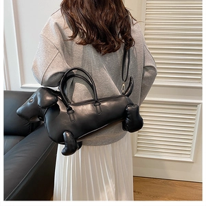 Modern black dachshund-shaped leather crossbody bag shown on a model from a back view