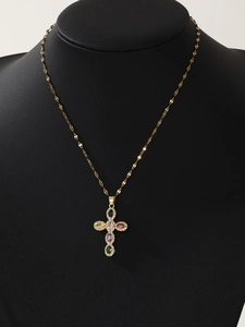 Detailed close-up of a golden cross necklace with colorful gemstones on a black mannequin