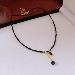 Detail of 18K gold-plated necklace featuring black beads and multifaceted crystal pendants