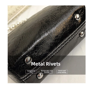 Macro shot of black leather bag with silver rivets and contrasting white stitching details