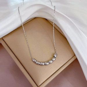 Silver bead necklace displayed in a gold gift box with white silk fabric detail