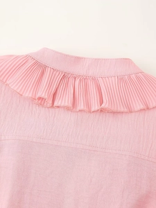 Close-up of pleated collar detail on pink chiffon shirt with textured woven fabric