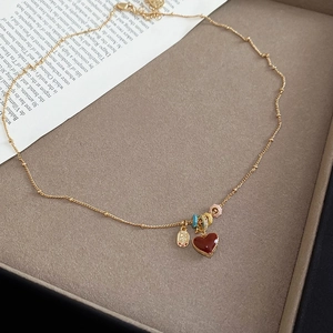 Detail of 18k gold plated necklace with red heart pendant on beige velvet tray