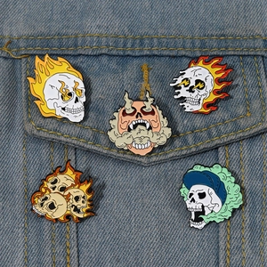 Detailed view of five unique horror skull enamel pins attached to a blue denim jacket pocket