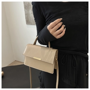 Detail of minimalist beige handbag showing the gold metal buckle and leather texture