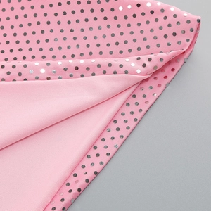 Vue détaillée du tissu en maille rose avec des paillettes argentées à pois brillants