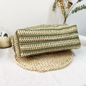 Detail view of woven raffia tote bag base featuring natural and dark green straw textures