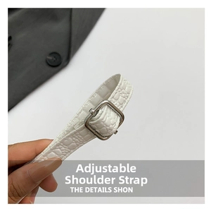 Detail of white crocodile embossed leather strap with adjustable silver metal buckle