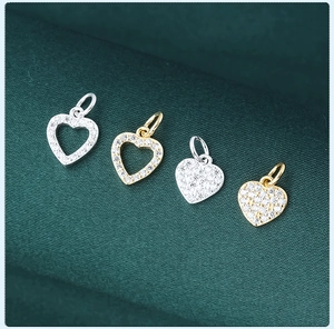 Macro detail of heart-shaped silver charms with sparkling pavé zircons on green fabric