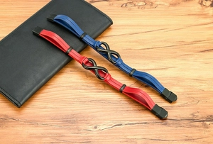 Detail view of red and blue braided leather bracelets with black infinity symbol clasp