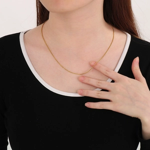 Close-up of a delicate golden stainless steel pearl chain necklace worn by a model
