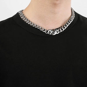 Close-up of polished silver Cuban chain necklace with a dark faceted gemstone pendant