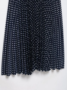 Detailed view of navy blue pleated midi dress with white polka dots and flowing fabric