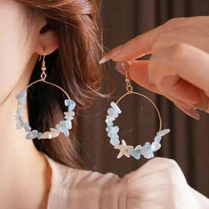 Golden hoop earrings with light blue sea stones and starfish charm on a female model