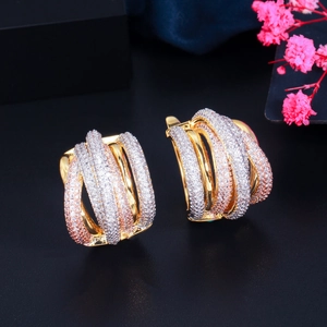 Detailed view of triple-tone twisted hoop earrings with pavé set zircon on black surface