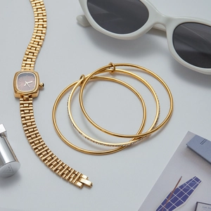 Golden quartz watch set with three cubic zirconia bracelets on a stylish magazine
