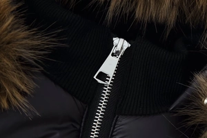 Close-up of metallic zipper and faux fur collar on the black winter cotton jacket