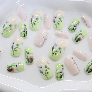 Unghie finte floreali verde pastello e rosa con motivi a fiori di lavanda su vassoio bianco