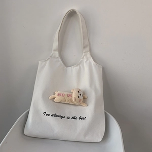 Detail of canvas tote bag featuring a 3D teddy bear plush and printed calligraphy