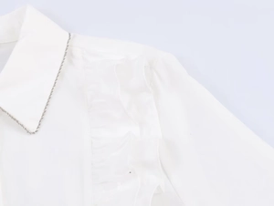 Detail of the white poplin shirt collar featuring elegant ruffled edges and bead trim