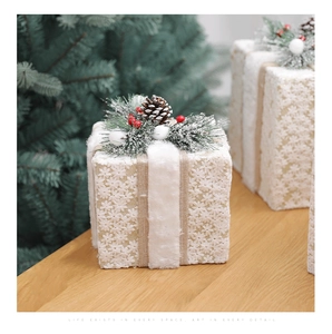 Close-up of white lace Christmas gift boxes with pine cones and red berries decor