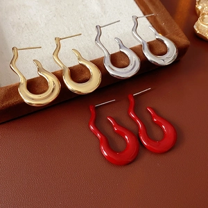 Detail shot of irregular wavy earrings in gold, silver, and red on a leather display