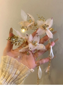 Dettaglio del fermaglio per capelli con fiori in tessuto rosa, perle e nappe dorate