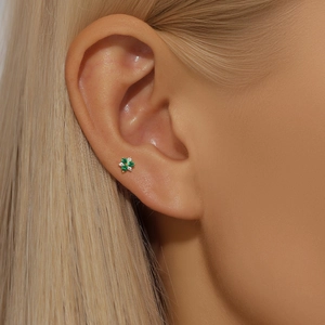 Close-up of elegant flower stud earrings with green and white gems on model's ear
